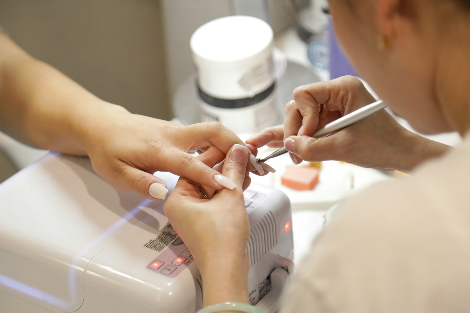 A nail technician painting a client's nails at a nail salon